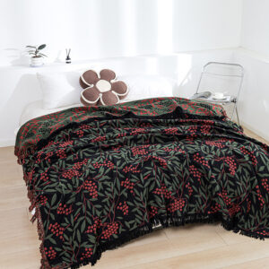 Red botanical woven throw blanket on bed with berry and leaf pattern