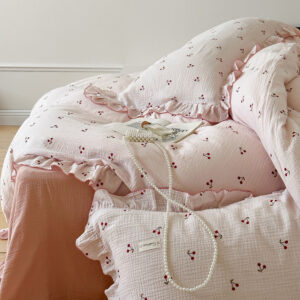 cherry print duvet cover set with ruffled edges in soft cotton muslin fabric on a light pink bed