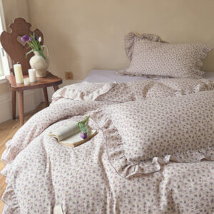 Purple floral duvet cover set with ruffled edges on a cozy bed
