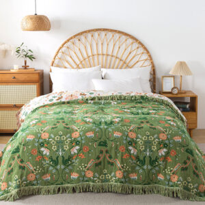 Botanical jacquard throw blanket in green laid on bed, reversible cotton design